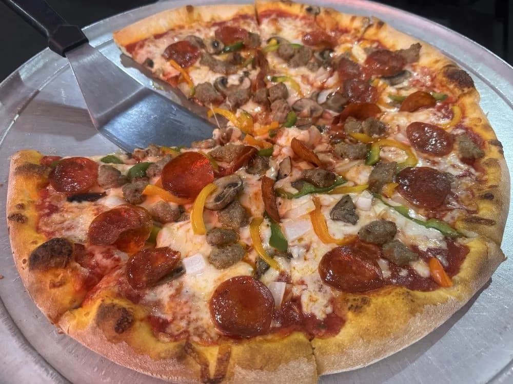 Whole hand-tossed pizza on a wooden peel